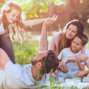 Family having fun outdoors, playing and laughing together on a picnic blanket